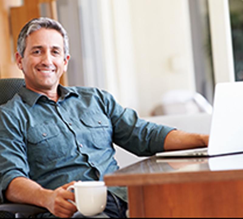 Photograph of man sitting at a desk smiling.